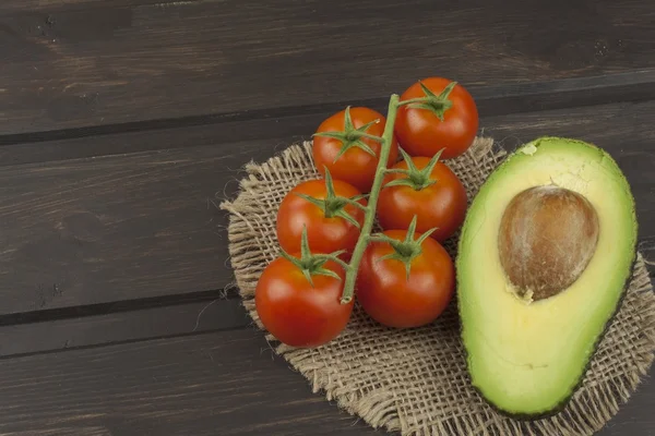 Preparation of dietary avocado salad. Fresh ripe avocado on a wooden background. Food background with fresh organic avocado. Avocado on a dark wood background.