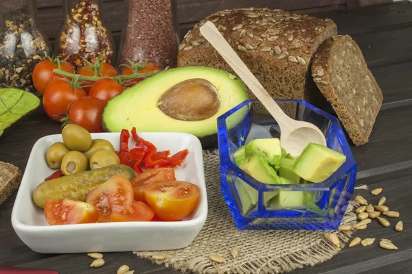 Preparation of dietary avocado salad. Fresh ripe avocado on a wooden background. Food background with fresh organic avocado. Avocado on a dark wood background