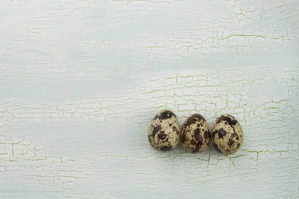 Перепелиные яйца трескались на белом фоне. Перепелиные яйца на старом потрескавшемся деревянном фоне . — стоковое фото