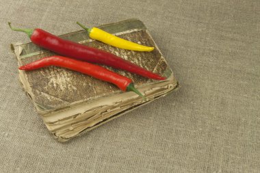 Chilies with an old recipe book. Vegetables ready for home cooking. Place for your text.