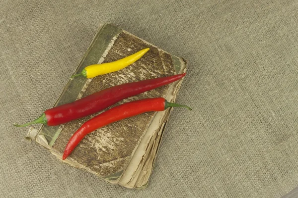 Chilies com um velho livro de receitas. Legumes prontos para cozinhar em casa. Lugar para o seu texto . — Fotografia de Stock