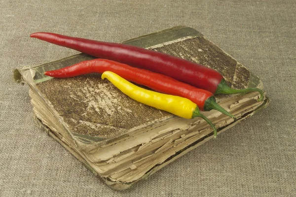 Chilies com um velho livro de receitas. Legumes prontos para cozinhar em casa. Lugar para o seu texto . — Fotografia de Stock