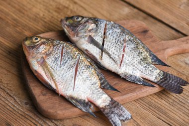 Taze tilapia balığı yemek pişirmek için / ahşap tahtada iki çiğ tilapia tatlı su balığı