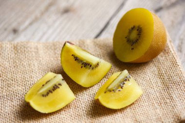 Çuval üstüne Kivi dilimi, ahşap arka planda sarı kivi meyvesi yakın plan. 