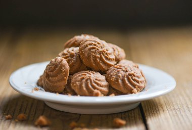 Beyaz tabakta çikolatalı kurabiyeler, ahşap arka plan, mini kurabiyeler.