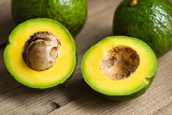 Avocado fruit and slice cut halfs avocado on wooden background, Fruits healthy food concept.