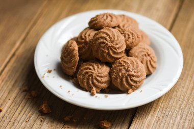 Beyaz tabakta çikolatalı kurabiyeler, ahşap arka plan, mini kurabiyeler.