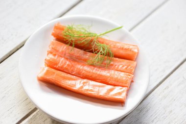 Yengeç çubukları beyaz tabakta ve sebzede, taze yengeç çubukları surimi Japon yemeği yemeye hazır