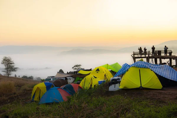 Camping tent area on mountain, tourist tent camping with fog mist landscape sunrise beautiful in winter view outdoor travel