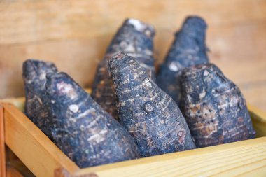 Taro kökü pişirmeye hazır. Tahta masada çiğ organik kahverengi taro.