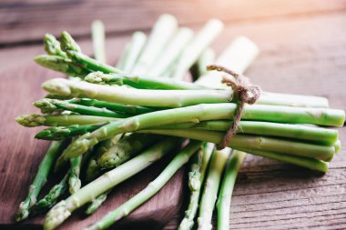 Köy ahşap bir masada bir demet taze kuşkonmaz pişmiş yemek için kuşkonmaz.