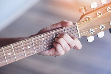 Erkek elleri akustik gitar çalar, akor gitaristi kapatır. Eğlenmek için müzik aleti ya da hobi tutkusu için seçici odaklanma.
