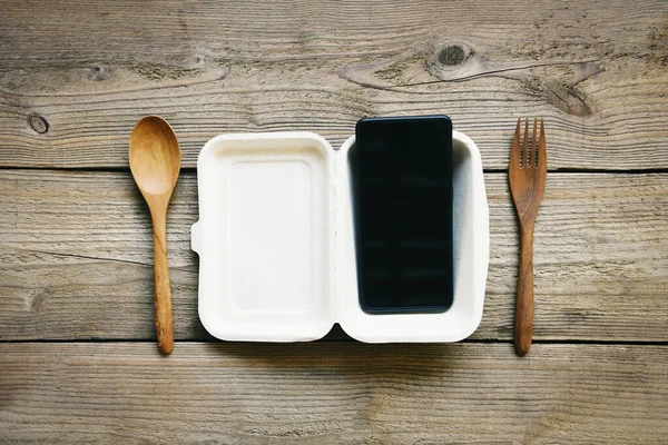 Call for delivery mobile food ordering concept, Service food take away delivery order online smart phone laying on plate and on the rustic wooden table - top view