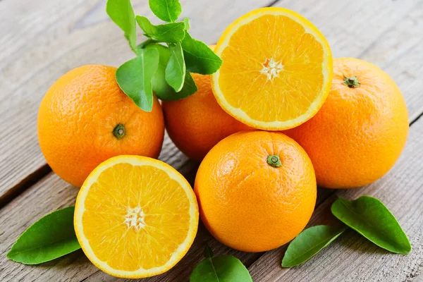 木の背景に葉を持つオレンジの果物 新鮮なオレンジのスライスと健康的な果物を残します — ストック写真