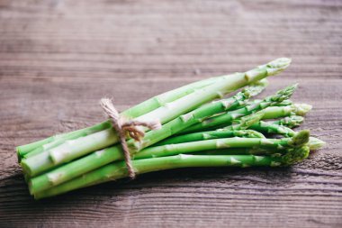 Pişmiş yiyecekler için kuşkonmaz, kırsal bir masada taze yeşil kuşkonmaz.