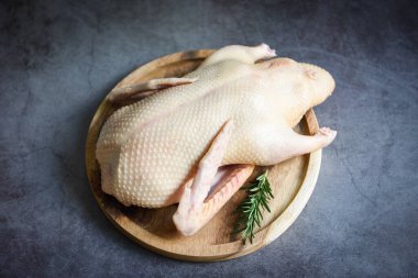 Bitkisel baharatlı çiğ ördek, arka planda pişmeye hazır biberiye, ahşap tepside taze ördek eti, tüm ördek - üst manzara