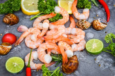 Taze karides ya da karides, deniz ürünleri ve baharatlı kabuklu deniz ürünleri, yemek pişirmek için koyu arkaplanda soyulmuş karides, üst manzara.