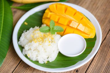 Hindistan cevizi sütüyle pişirilmiş olgun mango pilavı, yapışkan pirinç yaz tropik meyve Tayland tatlı mango kabuğu ve taze nane yaprağı.