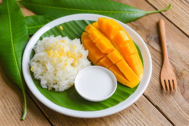 Hindistan cevizi sütüyle pişirilmiş olgun mango pilavı, yapışkan pirinç yaz tropik meyve Tayland tatlı mango kabuğu ve taze yaprak dilimleri.