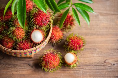 Rambutan fruit on basket and wooden background harvest from the garden, Fresh and ripe rambutan sweet tropical fruit peeled rambutan with leaves 