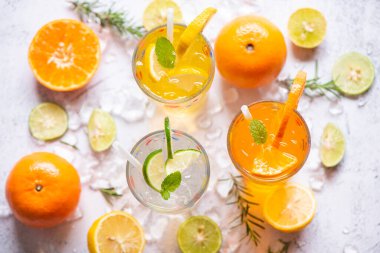 Renkli yaz içecekleri sulu, egzotik yaz içecekleri soğuk içecekler taze meyve bardakları buzlu ev yapımı kokteyl çayı limonlu, portakallı ve nane yapraklı.
