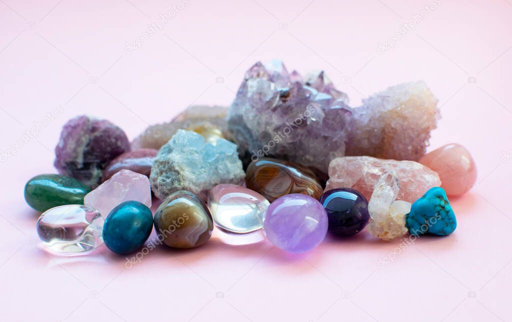 Tumbled and rough gemstones and crystals of various colors. Amethyst, rose quartz, agate, apatite, aventurine, olivine, turquoise, aquamarine, rock crystal. Selective focus.