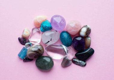Çalkalanmış ve pürüzlü değerli taşlar ve çeşitli renklerde kristaller. Ametist, gül kuvars, agate, apatit, aventurine, olivine, turkuaz pembe arka plan.