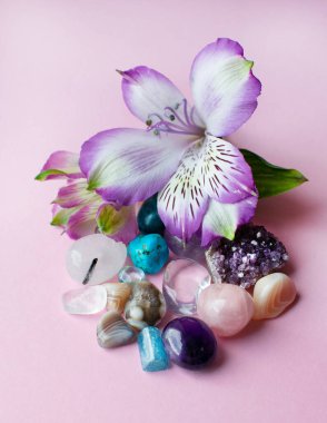 Ametist, yapay elmas, agate, gül kuvars, aquamarine ve alstroemeria çiçekleri pembe arka planda. 