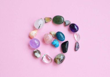 Çember doğal minerallerle kaplı. Farklı renklerde, işlenmemiş ve işlenmemiş yarı değerli taşlar. Ametist, gül kuvars, agate, apatit, aventurine pembe arka planda. 