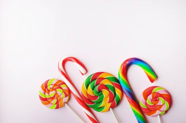 Renkli lolipoplar pembe bir arka planda çubuk şeker kamışları içinde. Düz yat, boşluğu kopyala