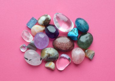 Çalkalanmış ve pürüzlü değerli taşlar ve çeşitli renklerde kristaller. Ametist, gül kuvars, agate, apatit, aventurine, olivine, turkuaz pembe arka plan.