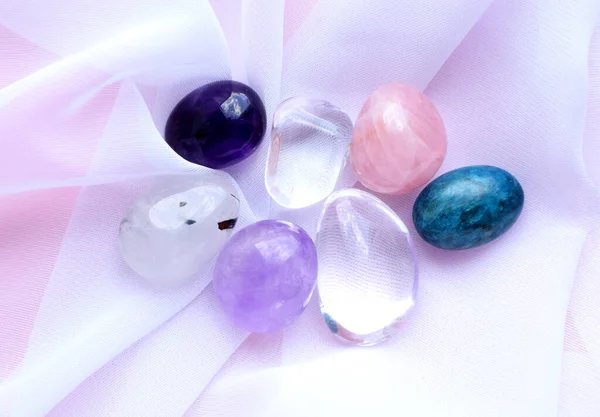 粉色背景上的宝石矿物 白色透明织物上的紫水晶 玫瑰石英 岩石晶体和磷灰石的圆形翻滚矿物 — 图库照片