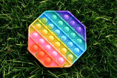 Renkli silikon renkli gökkuşağı antistresi yeşil çimenlikteki bebek için oyuncak. Üst görünüm.