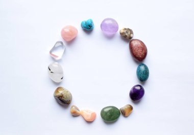 Çember doğal minerallerle kaplı. Farklı renklerde, işlenmemiş ve işlenmemiş yarı değerli taşlar. Ametist, gül kuvars, agate, apatit, aventurine beyaz arka planda. 