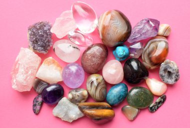 Çeşitli renklerde mücevherler. Amethyst, rose quartz, agate, apatit, aventurine, olivine, turkuaz, aquamarine, pembe arka planda kaya kristali