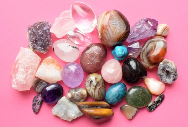 Gems of various colors. Amethyst, rose quartz, agate, apatite, aventurine, olivine, turquoise, aquamarine, rock crystal on pink background