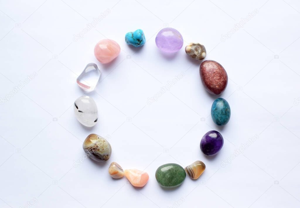The circle is lined with natural minerals. Semi-precious stones of different colors, raw and processed. Amethyst, rose quartz, agate, apatite, aventurine on a white background. 
