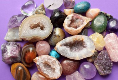 Çeşitli renklerde mücevherler. Jeot ametist, gül kuvars, agate, apatit, aventurine, olivine, turkuaz, aquamarine, mor zemin üzerinde kaya kristali