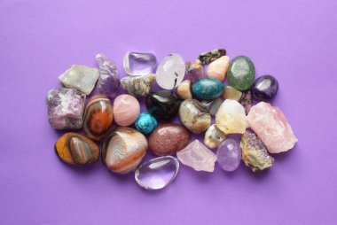 Çeşitli renklerde mücevherler. Amethyst, rose quartz, agate, apatit, aventurine, olivine, turkuaz, aquamarine, mor zemin üzerinde kaya kristali