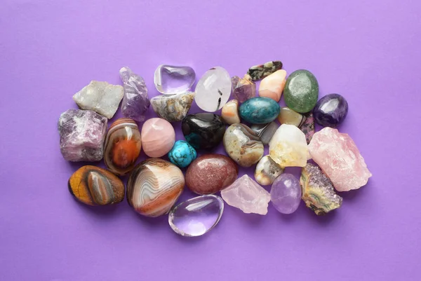 Gems of various colors. Amethyst, rose quartz, agate, apatite, aventurine, olivine, turquoise, aquamarine, rock crystal on purple background