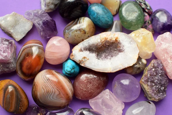 Gems of various colors. Geode amethyst, rose quartz, agate, apatite, aventurine, olivine, turquoise, aquamarine, rock crystal on purple background