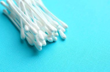 Mavi arka planda bir sürü plastik pamuklu çubuk var.. 