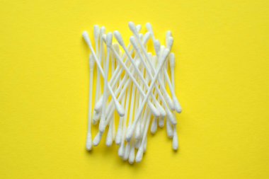 Sarı arka planda bir sürü plastik pamuklu çubuk var.