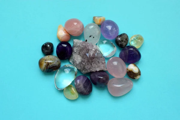 Gems of various colors. Amethyst, rose quartz, agate, apatite, aventurine, olivine, turquoise, aquamarine, rock crystal on blue background