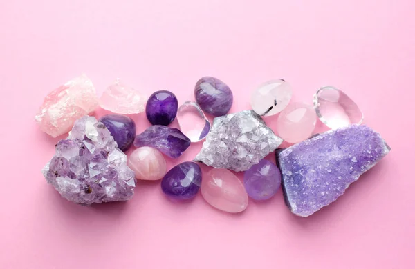 Beautiful gemstones and druses of natural purple mineral amethyst on a pink background. Amethysts and rose quartz. Large crystals of semi-precious stones.