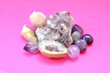 Güzel değerli taşlar, ametist jeotları ve parlak pembe arka planda doğal mor mineral ametistleri. Ametist ve gül kuvars. Yarı değerli taşların büyük kristalleri..