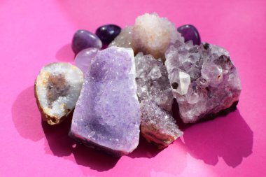 Güzel değerli taşlar, ametist jeotları ve parlak pembe arka planda doğal mor mineral ametistleri. Ametist ve gül kuvars. Yarı değerli taşların büyük kristalleri..