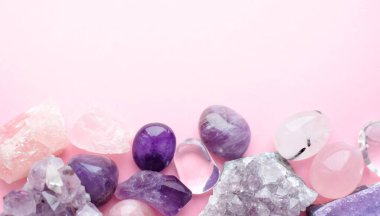 Pembe arka planda güzel değerli taşlar ve doğal mor mineral ametistleri. Ametist ve gül kuvars. Yarı değerli taşların büyük kristalleri..