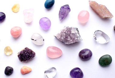 Farklı renkte mücevherler. Amethyst, rose quartz, agate, apatite, aventurine, olivine, turkuaz, aquamarine, sahte elmaslar beyaz arka planda bulunur. 
