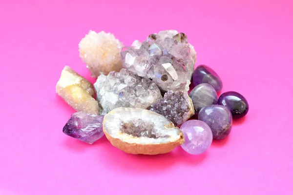 Beautiful gemstones,  geode of  amethyst and druses of natural purple mineral amethyst on a bright pink background. Amethysts and rose quartz. Large crystals of semi-precious stones.